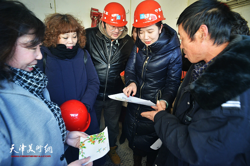 焦小红、赵新立、李悦在奇虎360EPC项目工地观看赵金良的绘画作品。