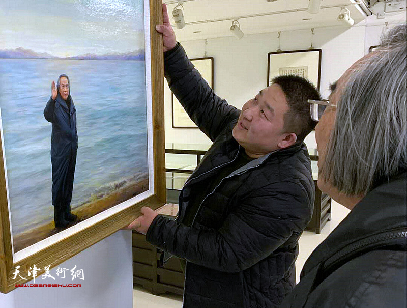 霍春阳仔细观赏写实油画《海边漫步》。