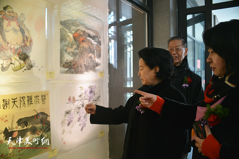 曹秀荣与参展作者在观看展出的作品。