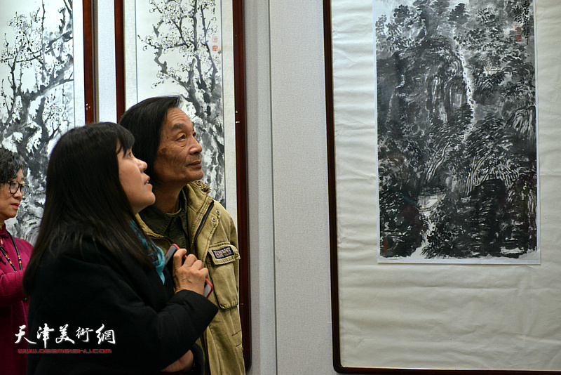 田耀泉、王洪春在画展现场观看作品。