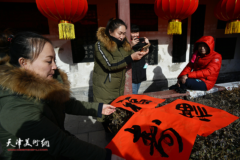 市民在现场看着心仪的福字，脸上洋溢着灿烂的笑容。