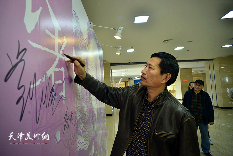 李桂金在签到墙上签名留念。