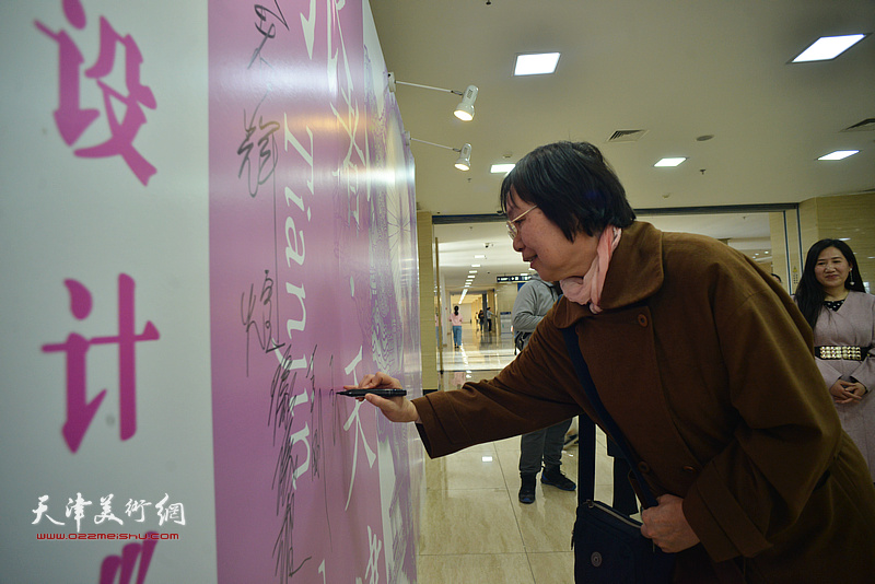 王玲在签到墙上签名留念。