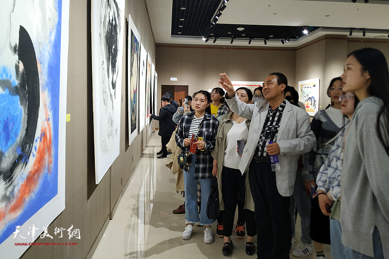 李寅虎在画展现场向学画的青年学生讲解作品。
