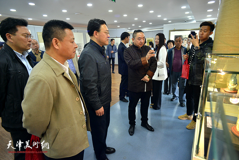 苗栋向周鸿滨等嘉宾介绍展出的国家级玉雕作品。