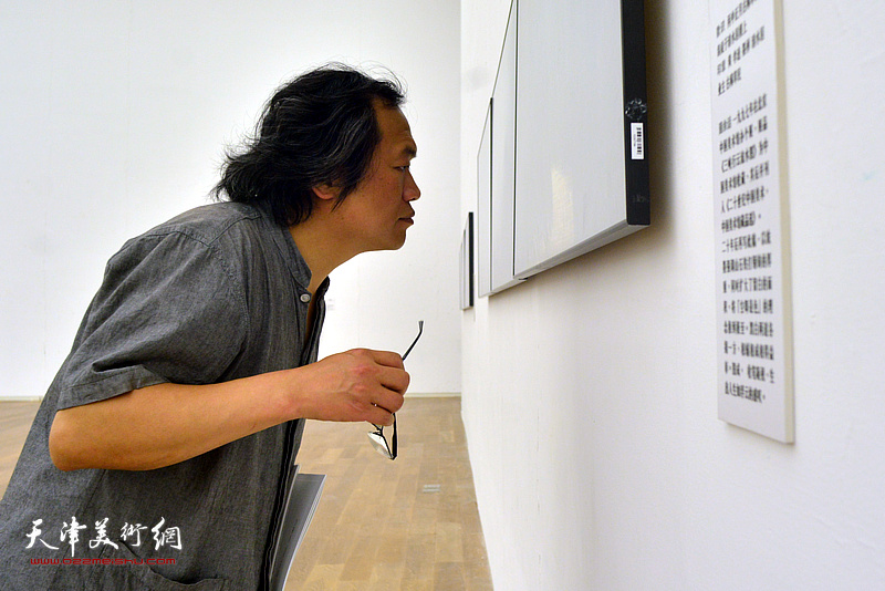 杨惠东在展览现场观看作品。