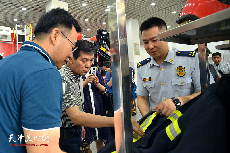 贺一哲向天津画院一行介绍消防装备器材。