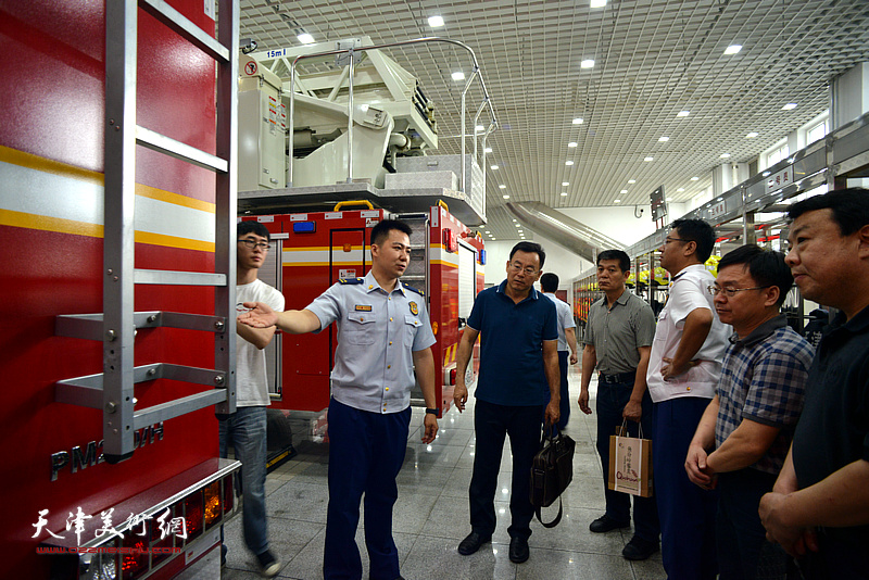 贺一哲向天津画院一行介绍消防装备器材。