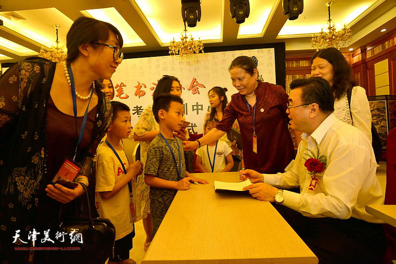 张华庆在揭牌仪式现场为小朋友签名留念。