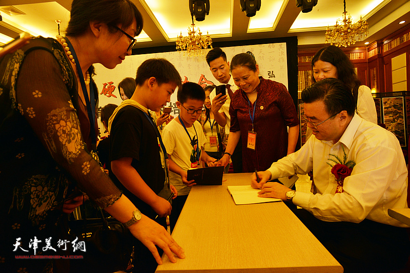 张华庆在揭牌仪式现场为小朋友签名留念。