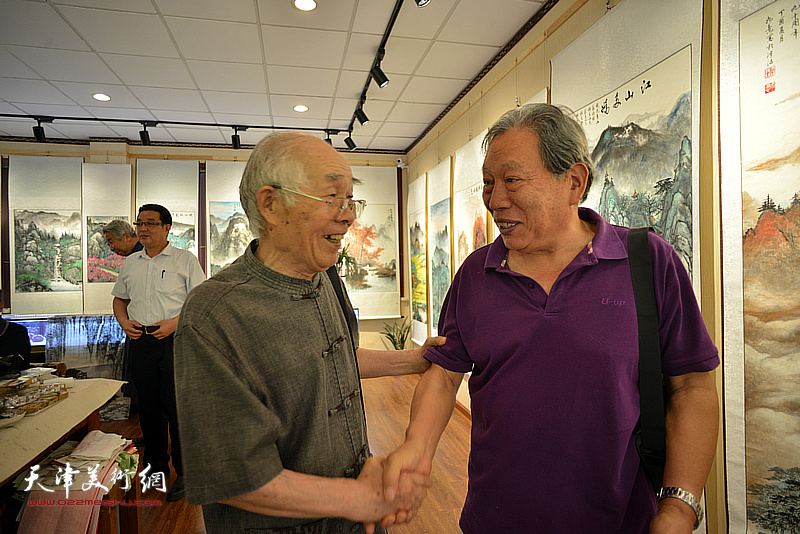 霍然、郭文伟在画展现场交流。