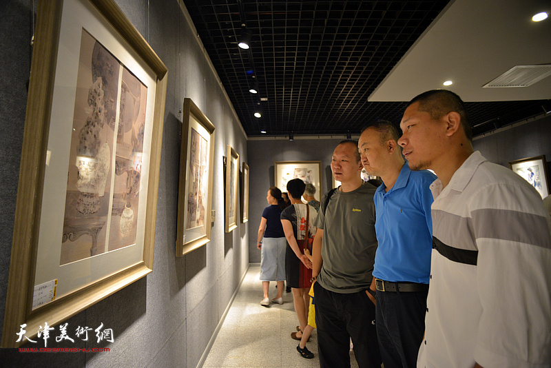 柴博森、何成、郑伟在画展现场观看作品。