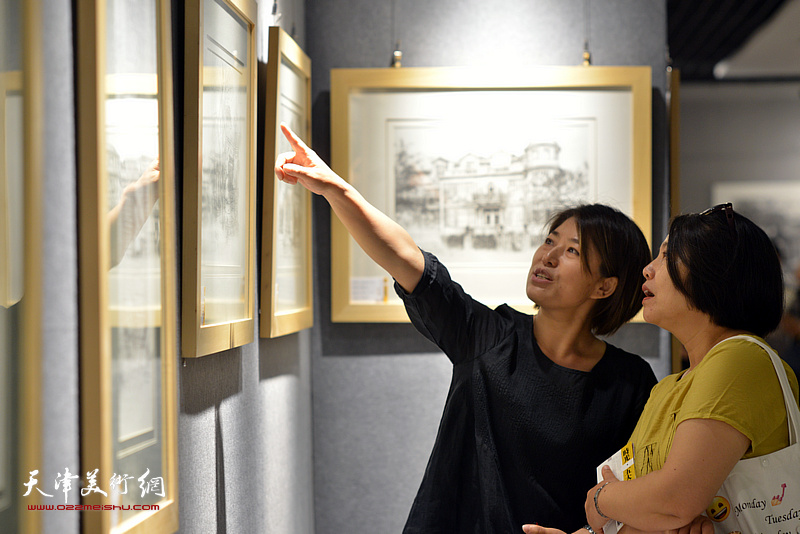 窦士萍与嘉宾在画展现场观看作品。