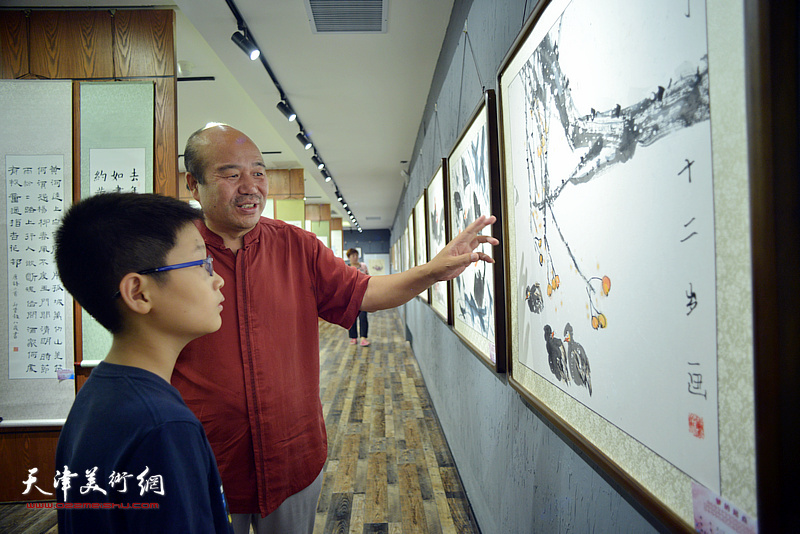 孟庆占与小作者娄嘉泰在大展现场观看作品。