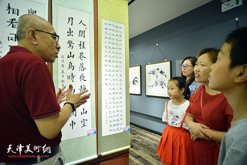 王炳学在大展现场与家长、小作者评点作品。