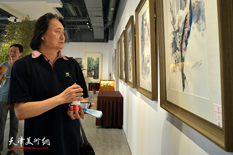 薛义观赏展出的彩墨作品。