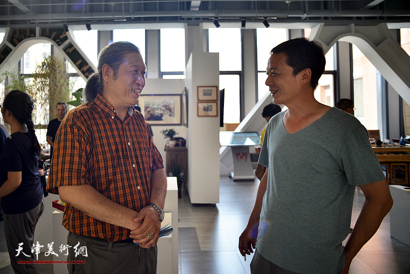 王刚、邵宏在彩墨作品展现场交流。