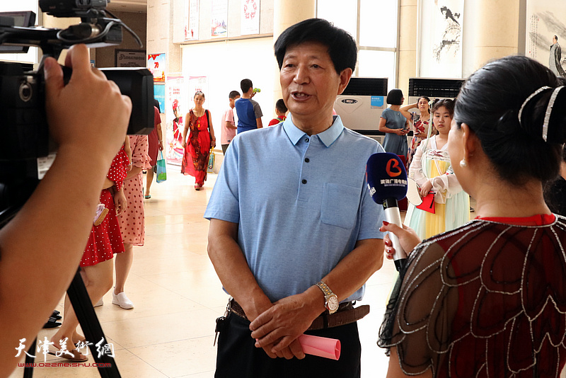 皓翔画院院长李守玉在画展现场接受媒体采访。