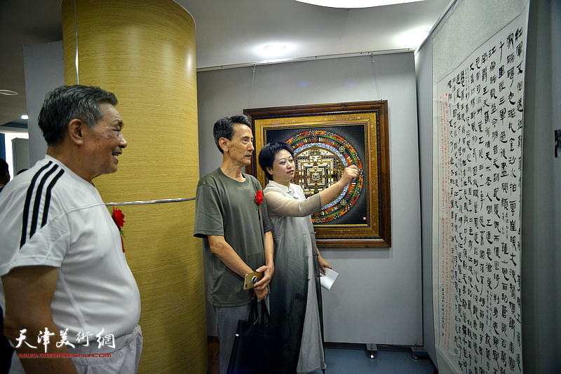 彭飞向李文安、顾富林介绍展出的书画作品。
