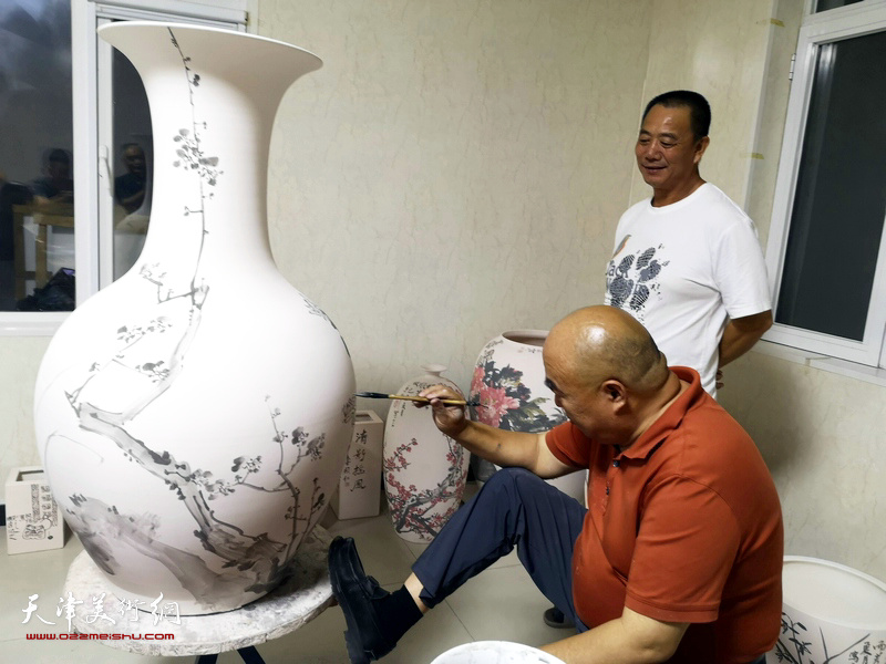 著名书画家尹沧海在北方陶艺中心创作青花瓷。旁为王树江。
