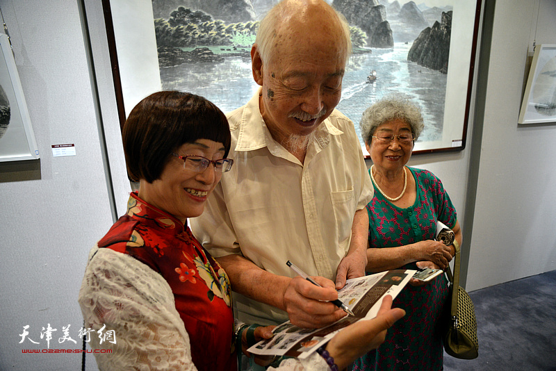 周志龙在画展现场为观众签名留念。