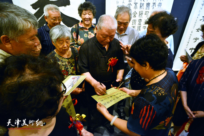 李家尧在展览现场为观众签名留念。