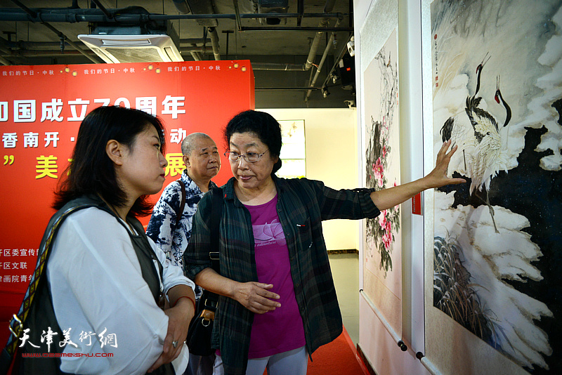 张永敬在展览现场为恒美松讲解作品。