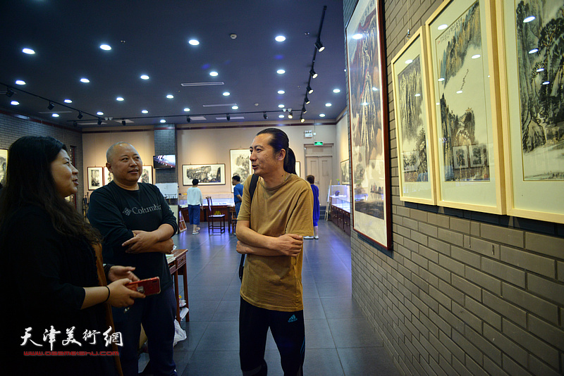 周凡、崔华炎、宋浩男在画展现场观看作品。
