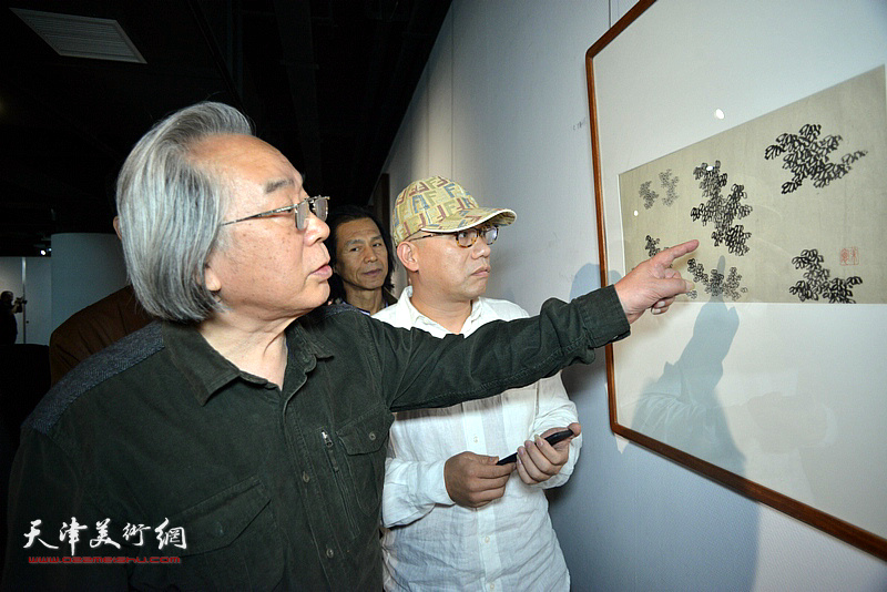 霍春阳、恒鑫在画展现场观赏展出的作品。
