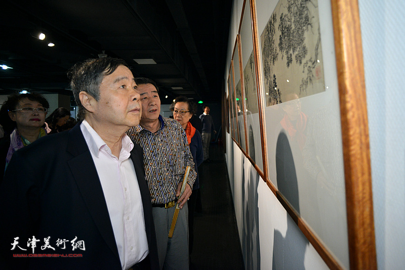 毓岳、毓震峰在画展现场观赏展出的作品。