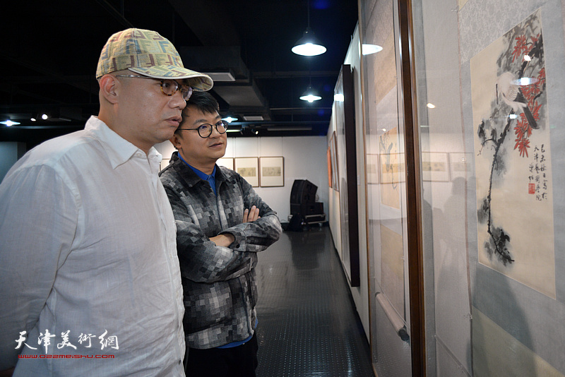 恒鑫、伯骧峰在画展现场观赏展出的作品。