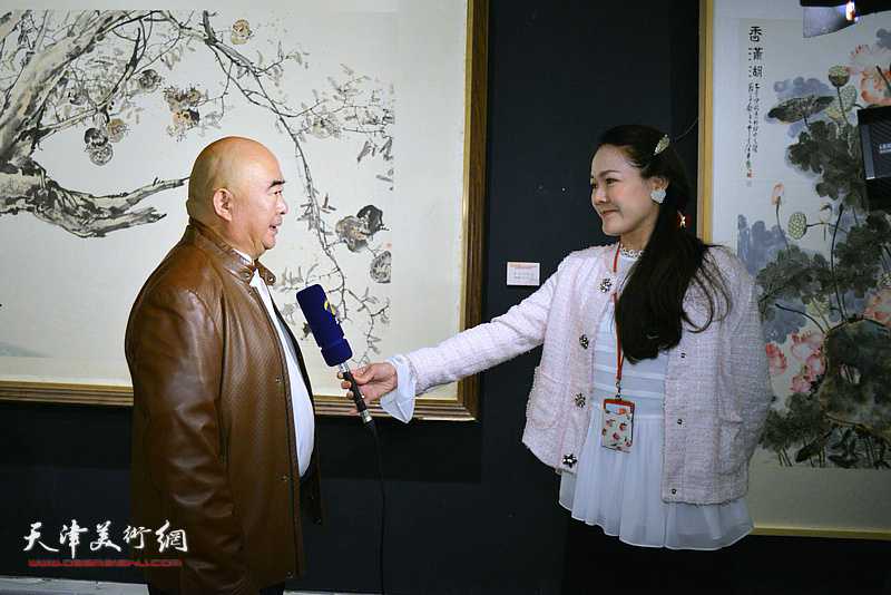 尹沧海在展览现场接受记者齐祺采访。