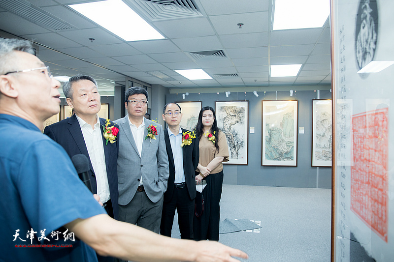杨维陪同嘉宾在观看展出的作品。