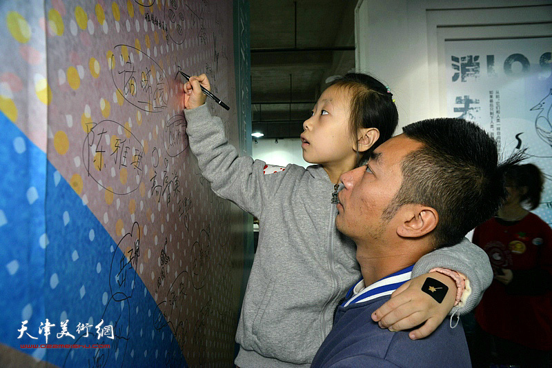小朋友在活动现场的签名墙上签名留念。