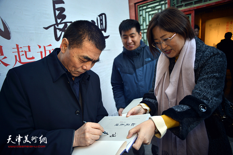 张根起为来宾在《松风长迴——张根起近作展作品集》上签名留念。