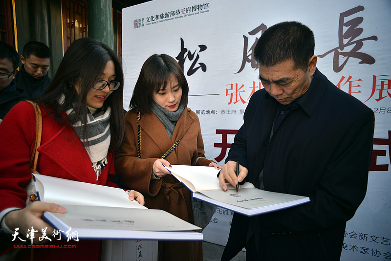 张根起为来宾在《松风长迴——张根起近作展作品集》上签名留念。