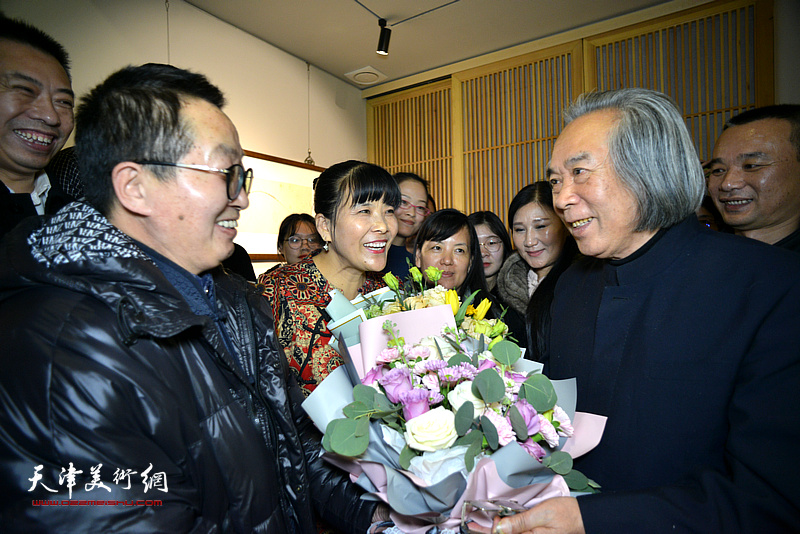 图为学生们向霍春阳教授献花，祝贺画展举办成功。