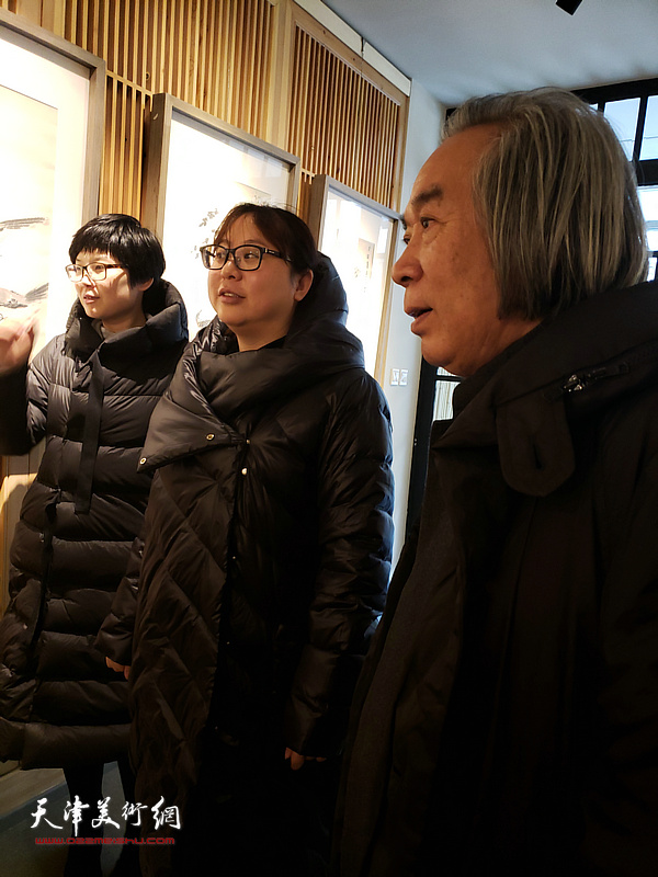 霍春阳先生与助手刘娜、谢雅云在“李亚精品展”现场观赏展出的画作。