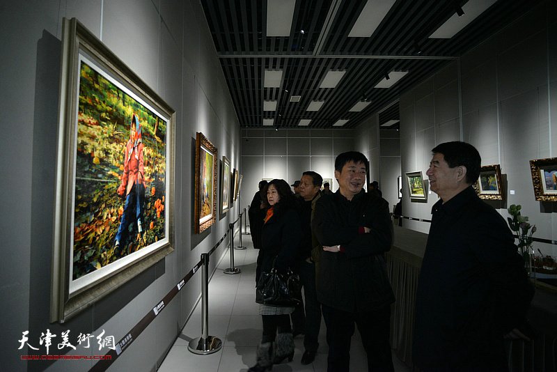 孟宪立与来宾在画展现场观赏展出的作品。
