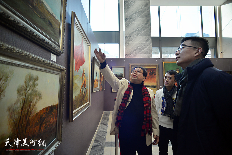 高建章向观众介绍展出的油画作品。
