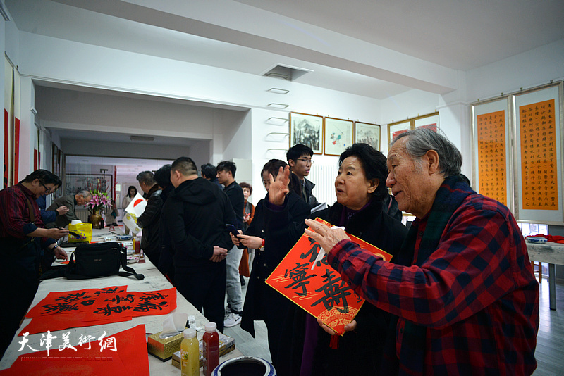 曹秀荣与姬俊尧观赏梅江书画院“文化过年”的书画展示。