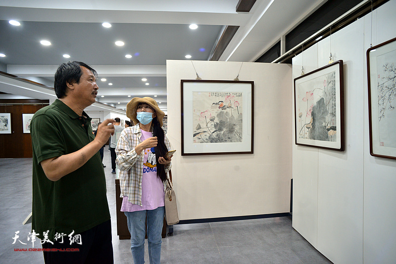赵振章与嘉宾在画展现场观看作品。