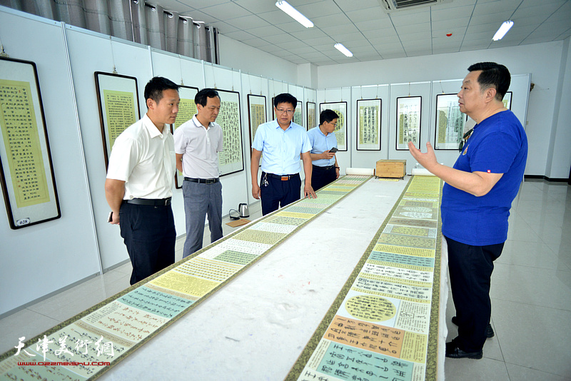 马巍华向雄安新区的嘉宾介绍“汉字历史艺术馆”展出的作品。