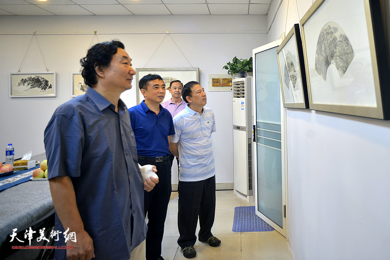 韩石、金石、陈国兴在三省斋观赏展出的扇面作品。