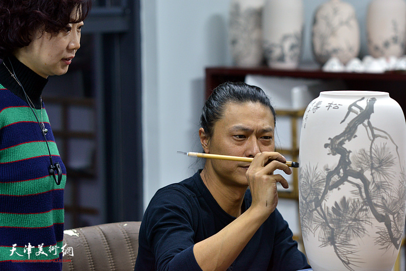 姚铸、朱珊在天津同飞书画院画青花瓷。