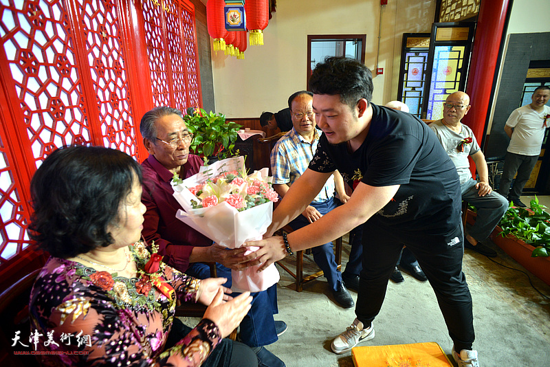 弟子杨斌向师父万珂新、师母于金兰献花。