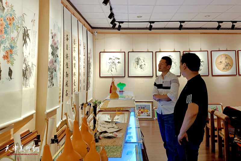 郑伟陪同来宾在展览现场观看作品。