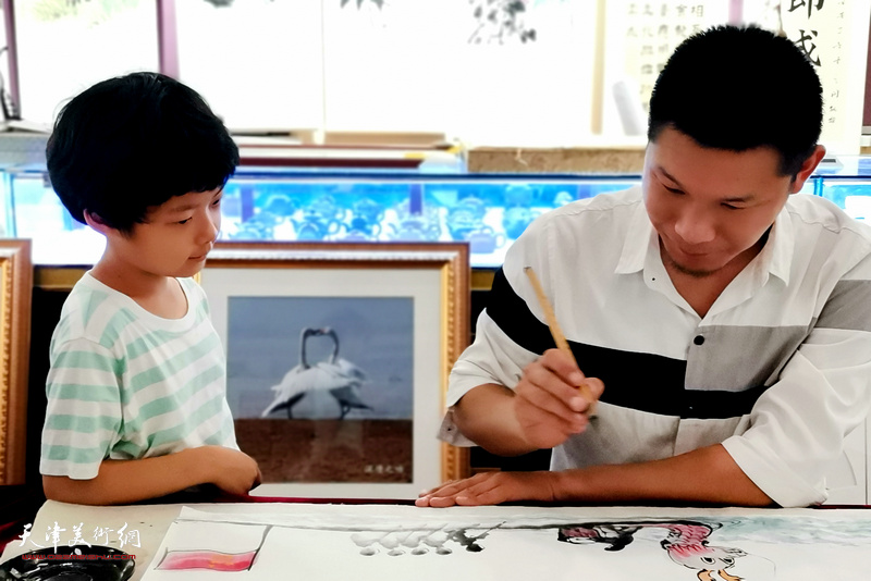 郑伟在展览现场为小画家示范。
