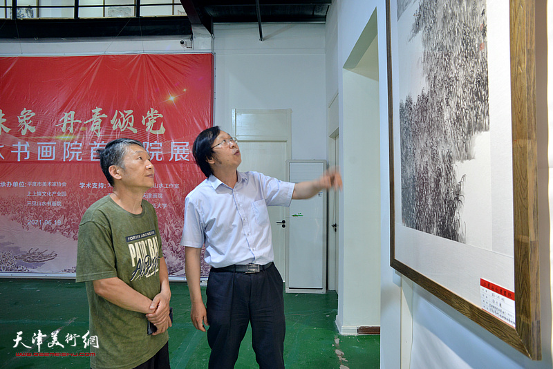 陈学文、路洪明在画展现场观看展出的作品。