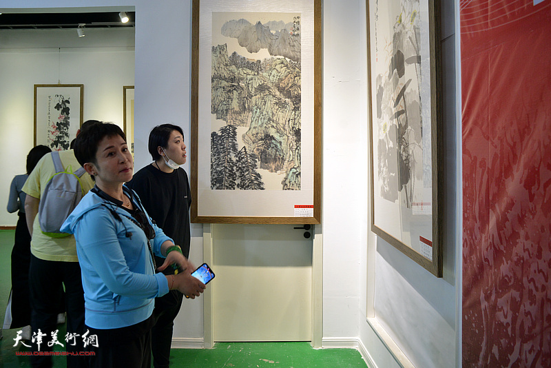 范馨心、王岚在画展现场观看展出的作品。